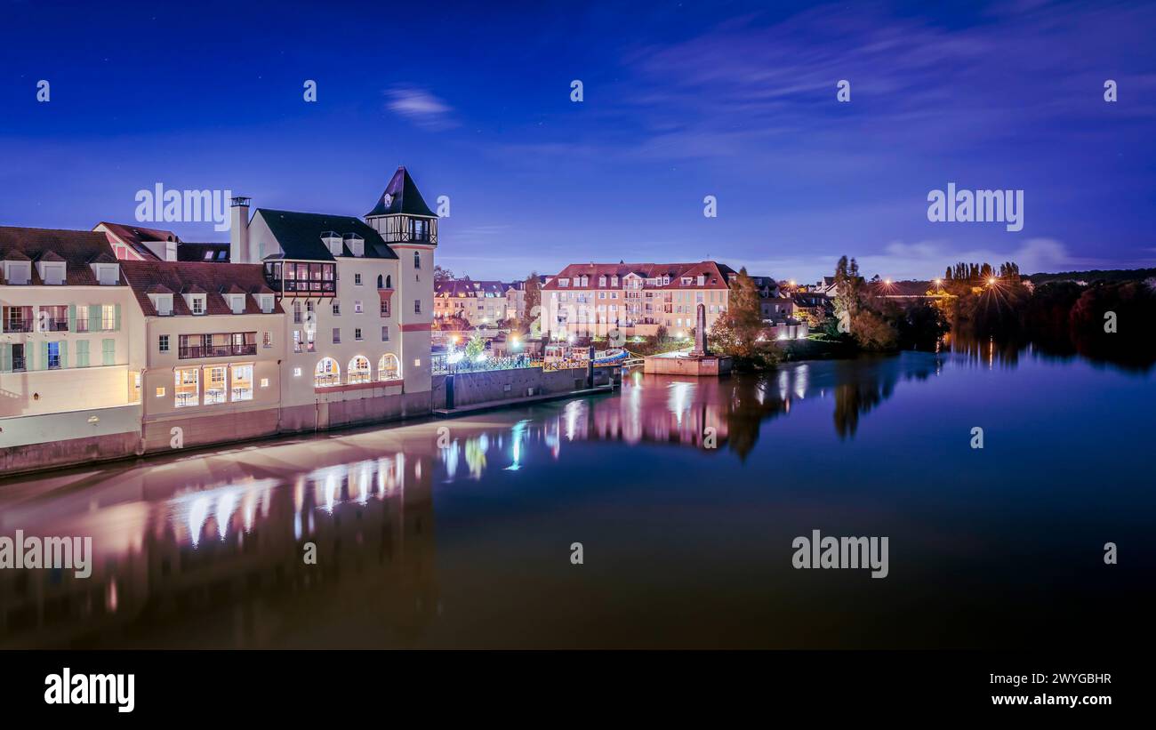 Malerische Stadtlandschaft mit Gebäuden und Straßenlaternen, die sich auf ruhiger Wasseroberfläche spiegeln Stockfoto