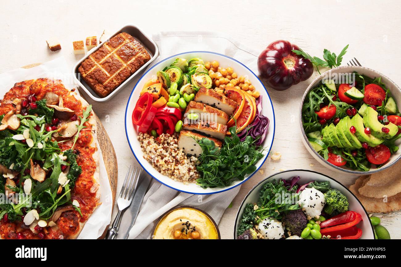 Vegetarisches Lebensmittelkonzept. Gesundes vegetarisches Essen, Salat, Avocado, Pizza und buddha Schüssel auf hellem Hintergrund, Blick von oben. Kopierbereich. Stockfoto