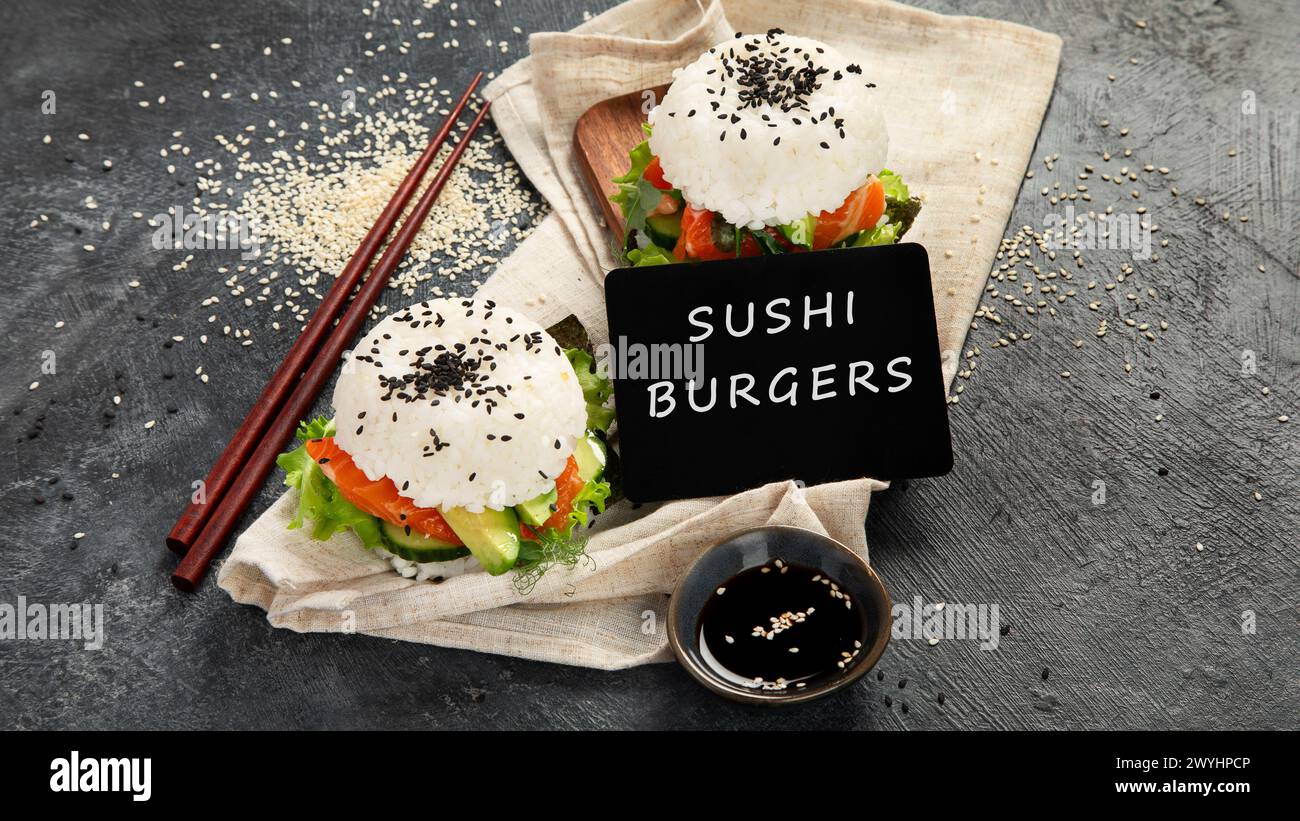 Asiatischer Sushi-Burger, Sojasauce, Essstäbchen auf dunklem Hintergrund. Trendiges Hybrid-Essen. Stockfoto