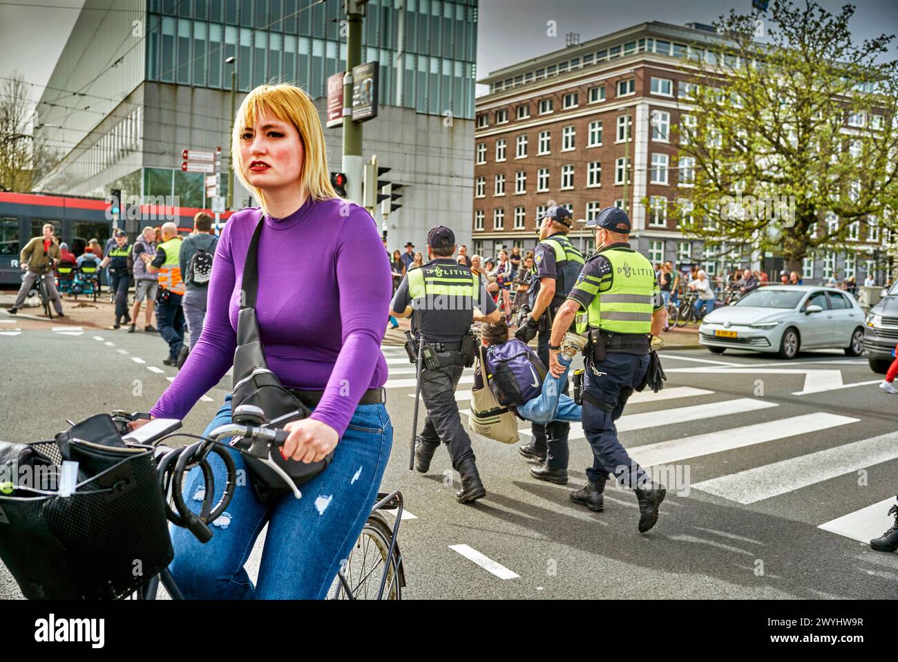 Eine Radfahrerin in den Haag versucht, ihren Weg zu finden, als die Proteste von XR von der Straße entfernt wird. Eine kleine Gruppe von Demonstranten blockierte die Straße (S100) im Zentrum von den Haag während einer Extinction Rebellion Bewegung. Anfangs wollten die Aktivisten die A12 zum 37. Mal blockieren, aber es gelang ihnen nicht, die Straße zu erobern, als Polizisten sie umzingelten und verhafteten. Die Demonstranten trugen „XR“-Flaggen und Plakate mit der Aufschrift „Stop Fuel Subventionen now!“ Und „der Planet stirbt!“. (Foto: Norbert Voskens/SOPA Images/SIPA USA) Stockfoto