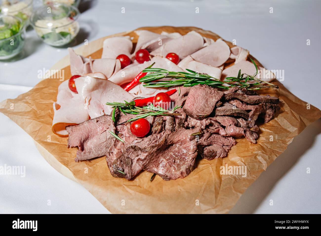 Eine Platte mit Aufschnitt mit truthahnscheiben, Roastbeef, garniert mit Kirschtomaten und frischen Rosmarinzweigen. Stockfoto