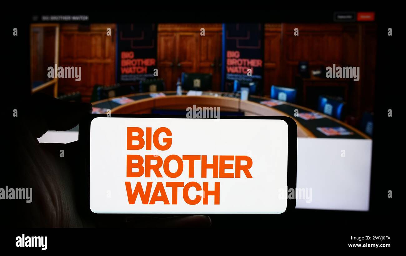 Person, die ein Handy mit dem Logo der britischen Wahlkampforganisation Big Brother Watch vor der Webseite hält. Schwerpunkt auf dem Display des Telefons. Stockfoto