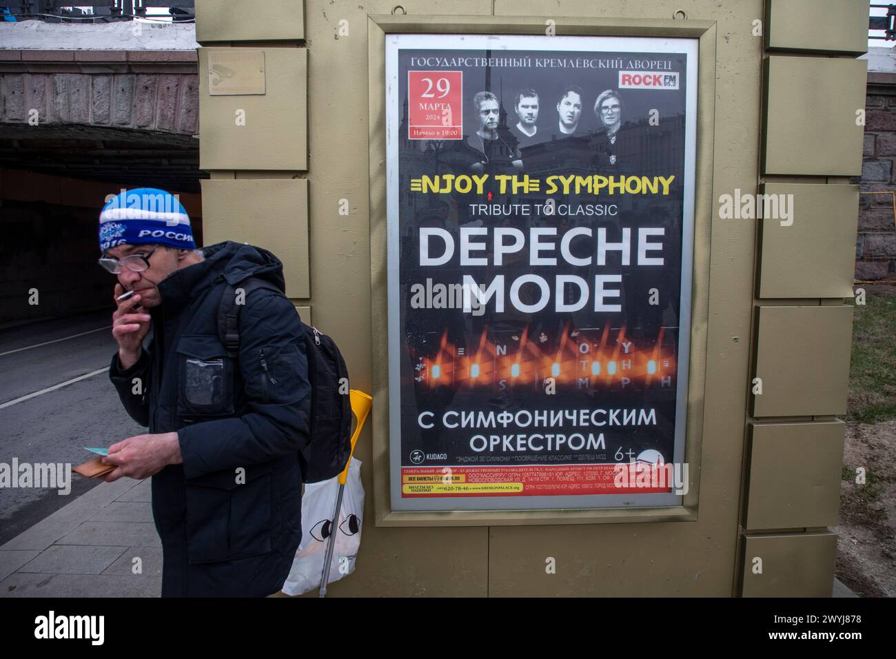 Moskau, Russland. 6. April, 2024. Ein Mann raucht auf einem Hintergrund eines Werbebanner des Rockkonzerts des Depeche Mode englische elektronische Musik auf einer Straße im Zentrum von Moskau, Russland Stockfoto