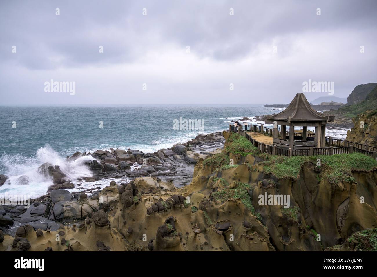 Bedeckte Küstenlandschaft mit einem traditionellen Pavillon auf einzigartigen Felsformationen mit Blick auf turbulente Wellen Stockfoto
