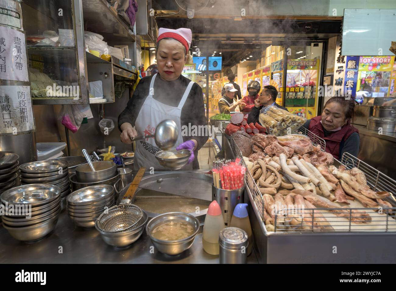 Ein Straßenverkäufer bereitet ein Gericht am Straßenrand mit einer Vielzahl von Fleisch zu Stockfoto