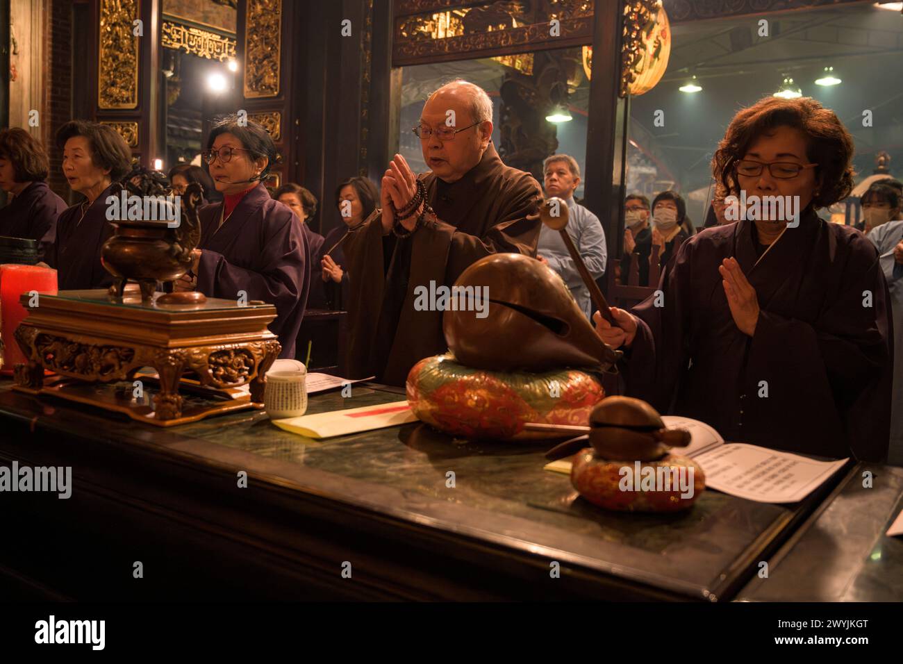 Ein Mönch, der tief in das Gebet vertieft ist, indem er Gebetskegeln während einer feierlichen religiösen Zeremonie des chinesischen Neujahrs verwendet Stockfoto