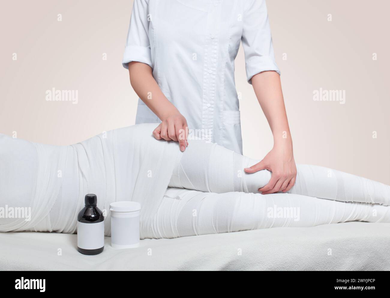 Die kosmetologin wickelt das Bein des Kunden. Anti-cellulite-Verfahren - STYX wickeln. Stockfoto
