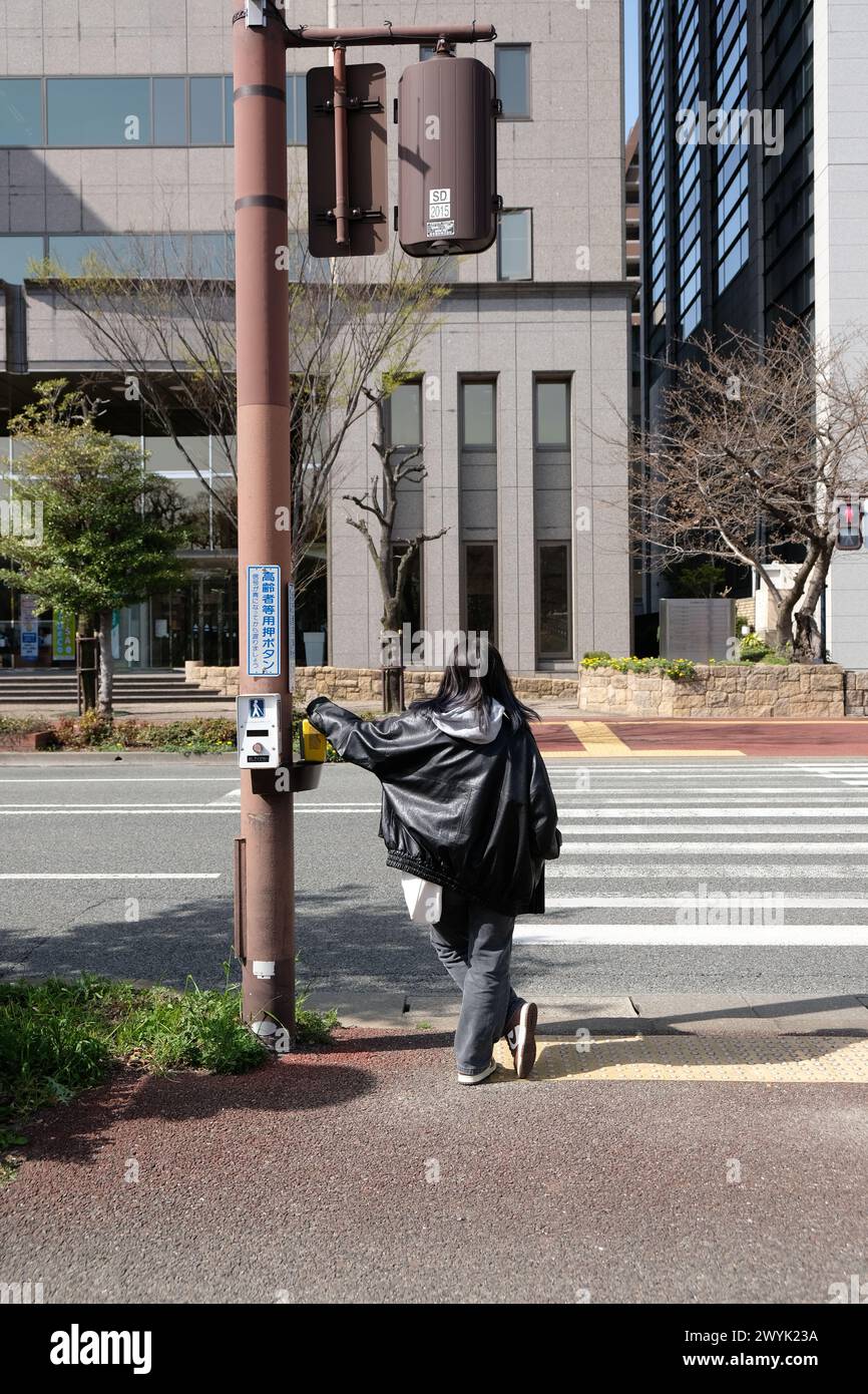 Stilvolle junge japanische Dame in Lederjacke, die an der Ampel wartet Stockfoto