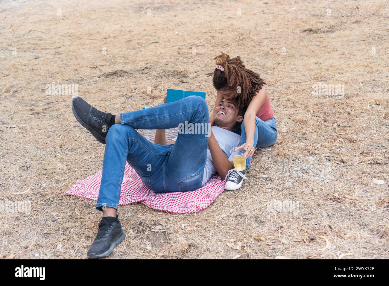 Eine Frau lehnt sich bei einem Picknick in spielerischer Pose über den Mann. Stockfoto