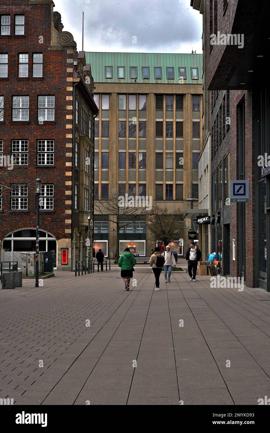 Portraitansicht einer Hamburger Straße, mit verschiedenfarbigen Gebäuden, die am Osterwochenende vorbeigehen, mit dem Logo der Deutschen Bank an der Seite Stockfoto