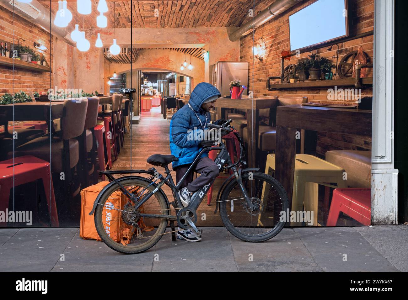 Lebensmittelzustellkurier Radfahrer überprüft sein Handy in der Princes Street, Edinburgh, Schottland, Großbritannien. Stockfoto