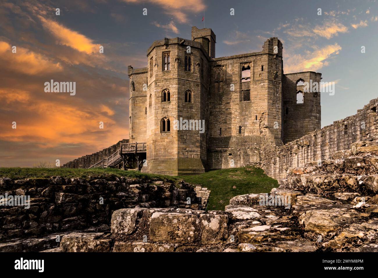 WARKWORTH CASTLE, NORTHUMBERLAND, GROSSBRITANNIEN - 16. MÄRZ 2024. Der befestigte kreuzförmige Donjon von Warkworth Castle und Ruinen mit dramatischem Himmel bei Sonnenuntergang Stockfoto