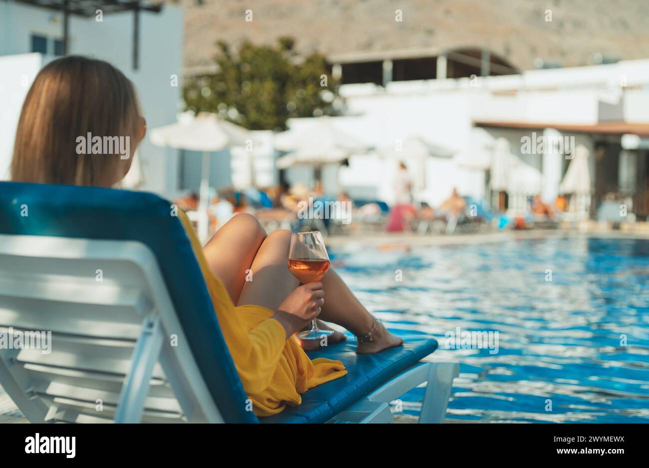 Frau mit Wein, die sich am Swimmingpool entspannt. Stockfoto