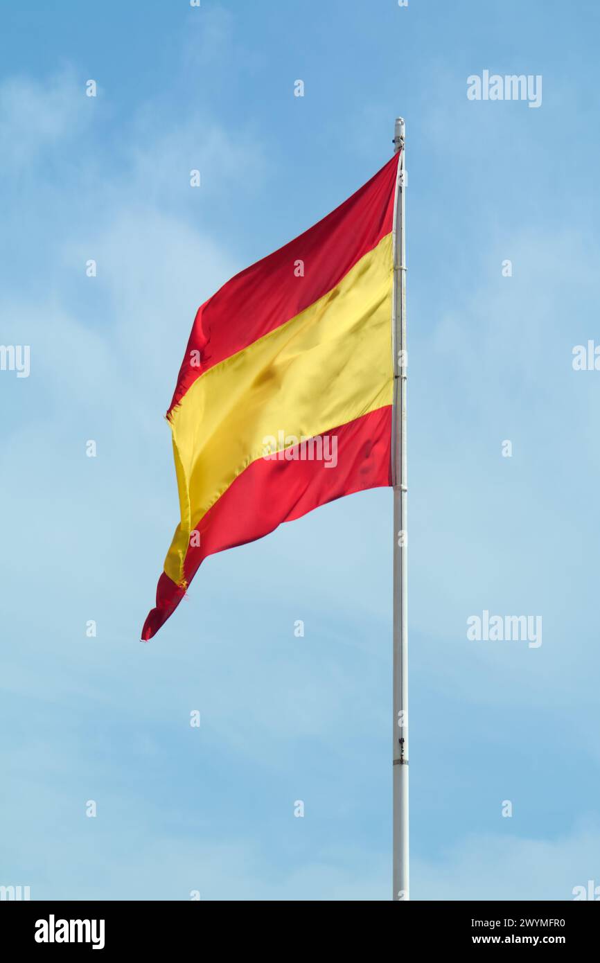 Die Nationalflagge Spaniens fliegt stolz unter einem blauen Himmel, ihre roten und gelben Farben leuchten in der Sonne und erinnern an den Geist und die Tradition des Grafen Stockfoto
