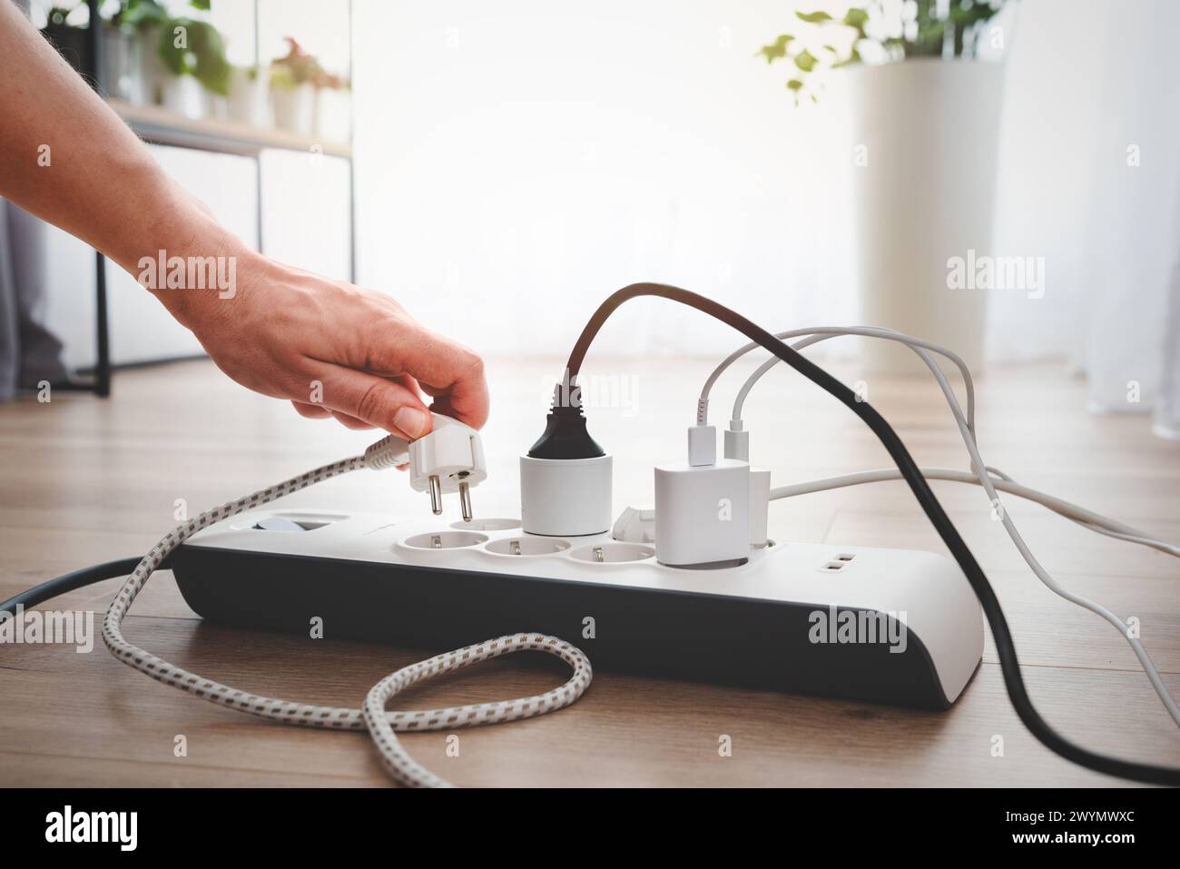Mann, der den Netzstecker einsteckt. Steckdose zu Hause. Stockfoto