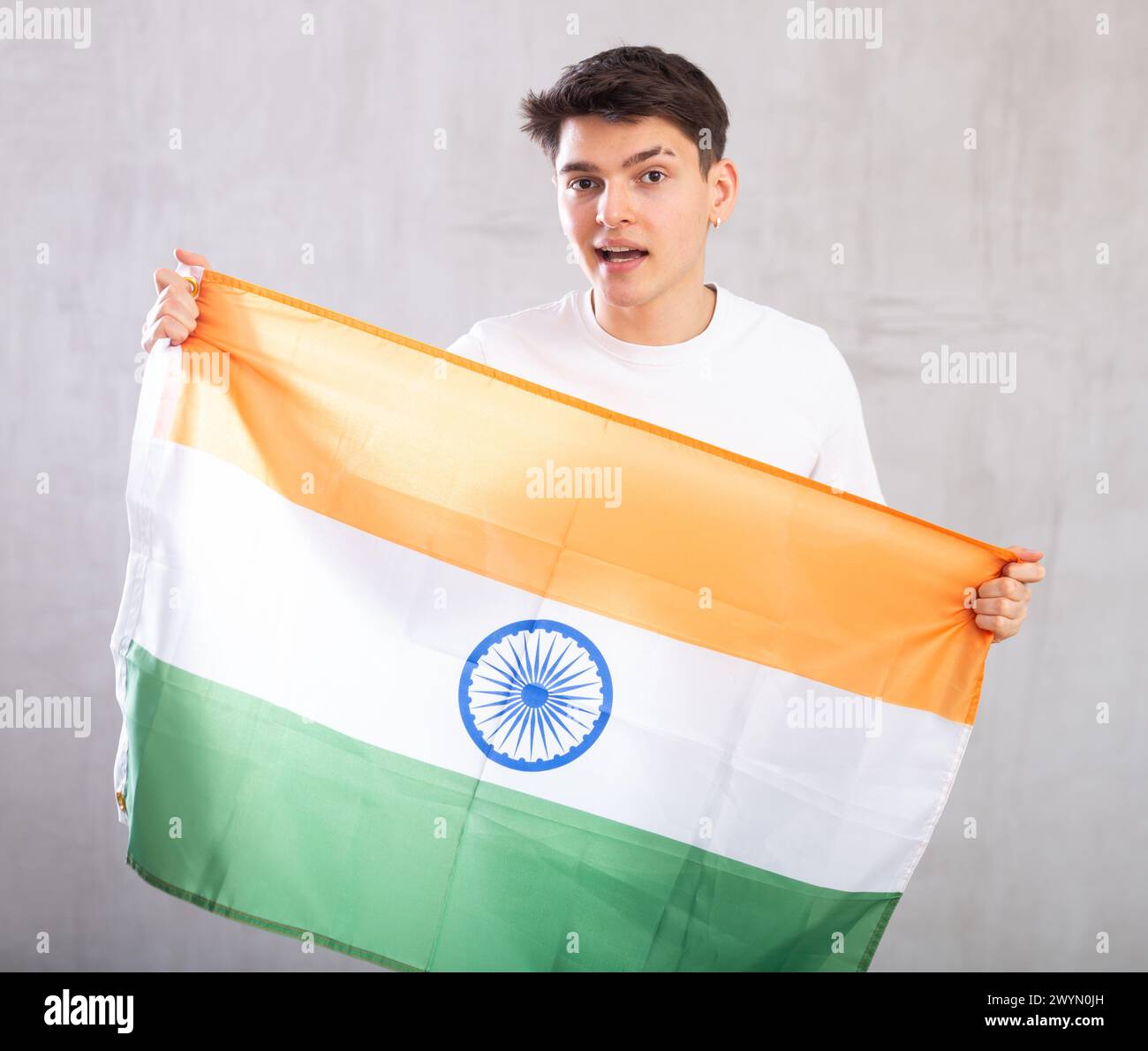 Der aktive männliche Zuschauer hält die Nationalflagge Indiens in den Händen und singt einen populären Slogan. Stockfoto