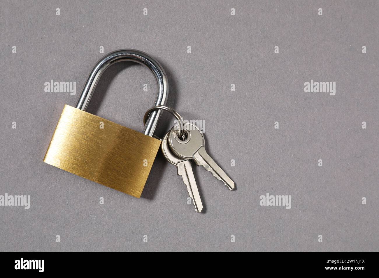 Vorhängeschloss aus Stahl mit Schlüsseln auf grauem Hintergrund, Draufsicht. Leerzeichen für Text Stockfoto