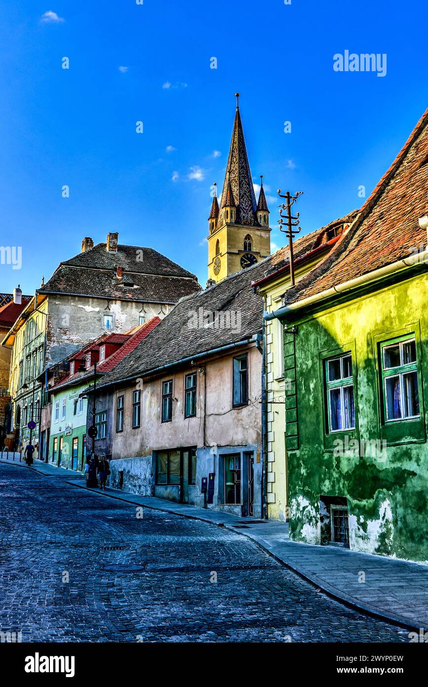 Häuser mit Augen, die die Strada Ocnei säumen, und die Spitze des Uhrenturms der Evangelischen Kathedrale St. Maria in Sibiu, Transsilvanien, Rumänien Stockfoto
