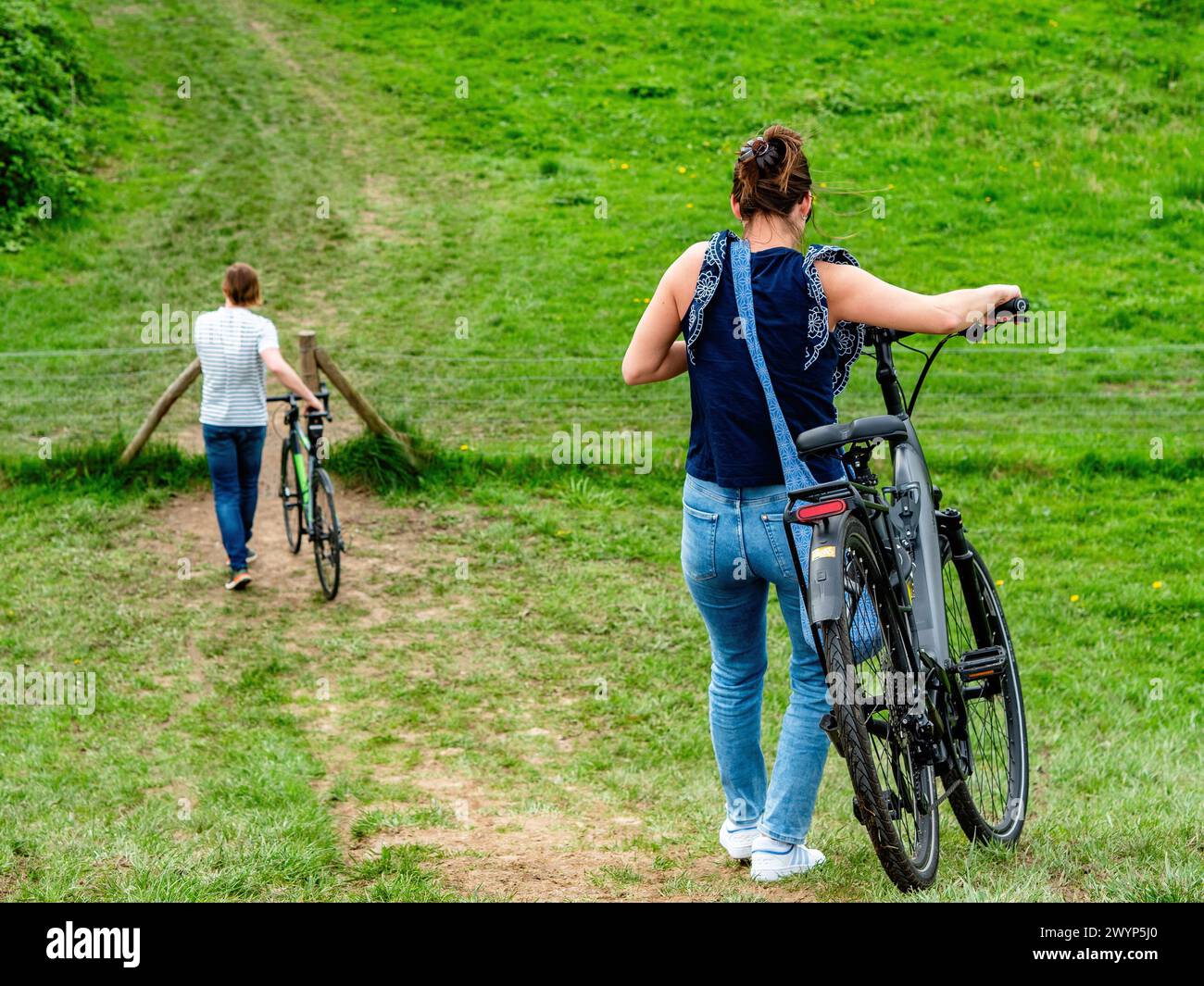 Nijmegen, Niederlande. April 2024. Man sieht ein Paar, das mit ihren Fahrrädern den Deich herunterfährt. Dieser Samstag war der erste offizielle warme Tag des Jahres und der wärmste 6. April aller Zeiten. Das Wetter kann im April in beide Richtungen gehen, und die aktuelle Periode zeigt dies auch schön. Aus diesem Grund nutzten die Leute dieses warme Wetter, um einen Spaziergang zu machen, die Natur zu genießen, Fahrrad zu fahren oder auf einer Terrasse im Zentrum der Städte zu trinken. (Foto: Ana Fernandez/SOPA Images/SIPA USA) Credit: SIPA USA/Alamy Live News Stockfoto