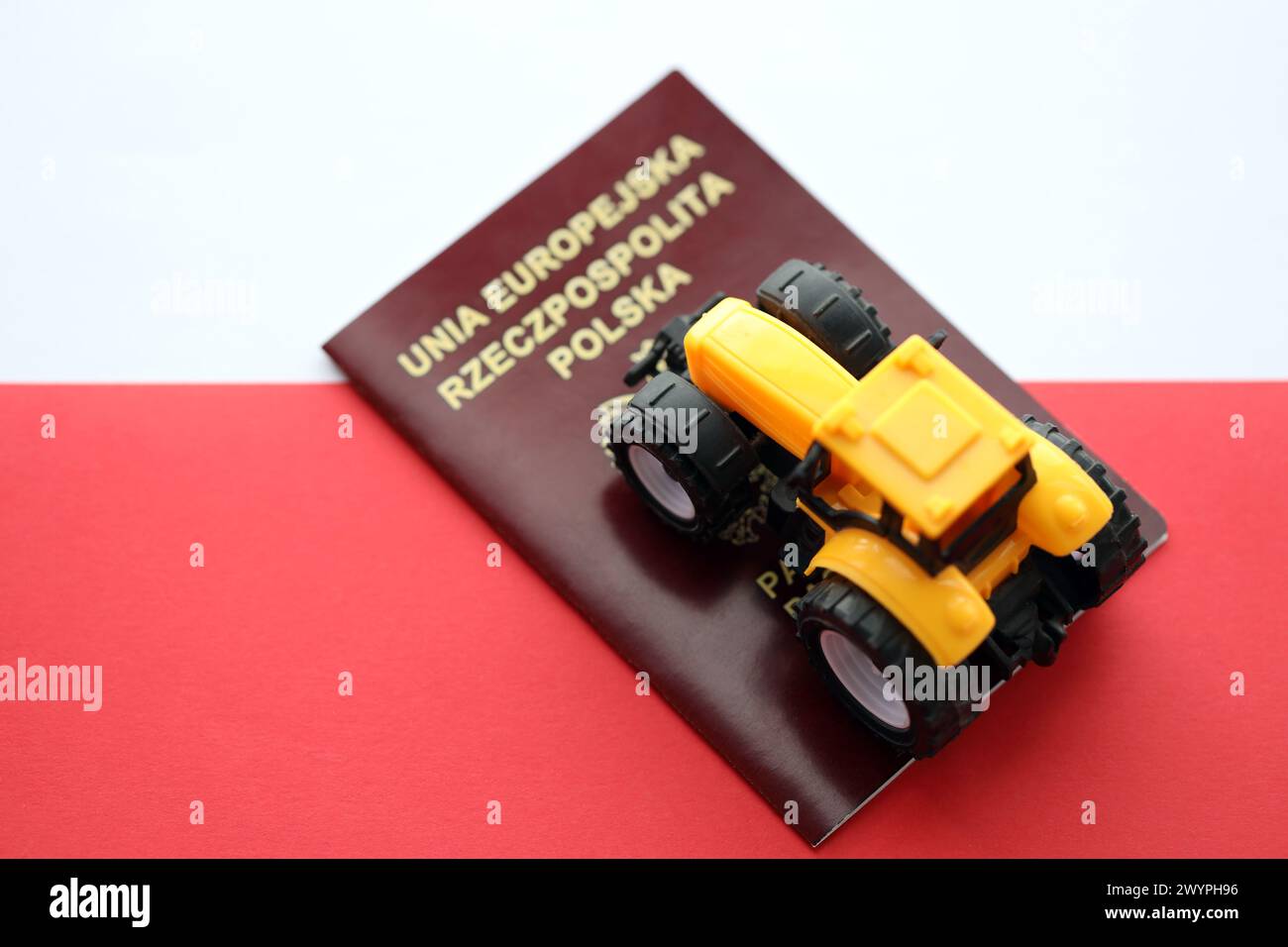 Roter polnischer Pass und gelber Traktor auf glatter rot-weißer Flagge von Polen Nahaufnahme Stockfoto