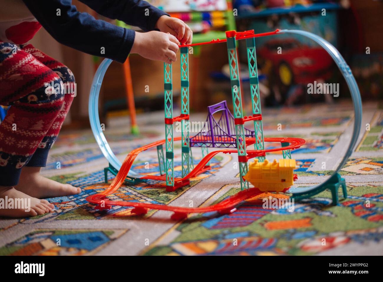 Kind spielt mit Spielzeug im Zimmer auf dem Farbteppich Stockfoto