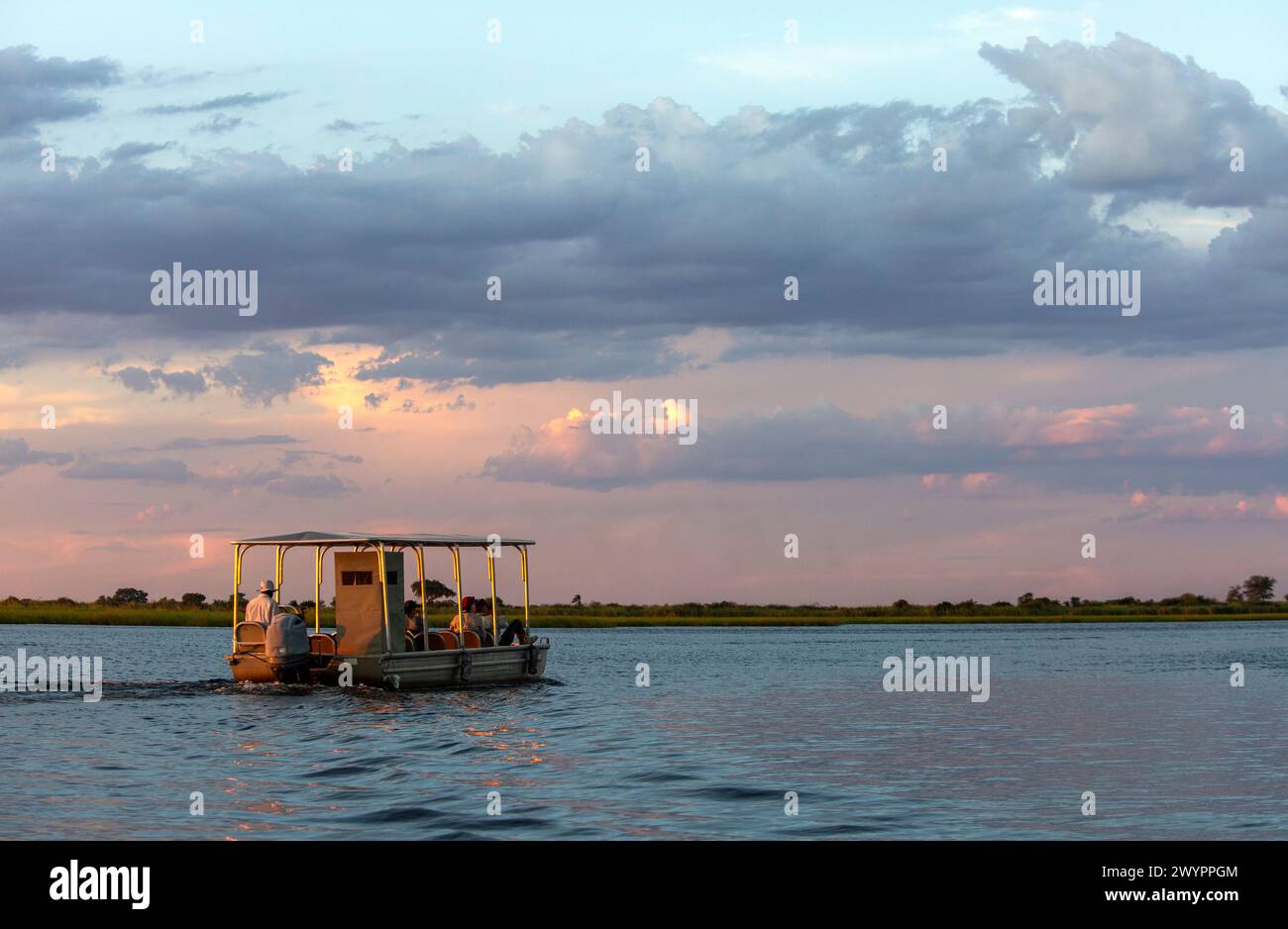 Ein Touristenboot auf einer Sundowner-Bootstour auf dem Chobe River im Chobe National Park Stockfoto