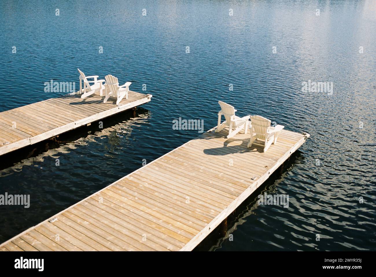 Ruhiges Dock am See mit Adirondack-Stühlen Stockfoto