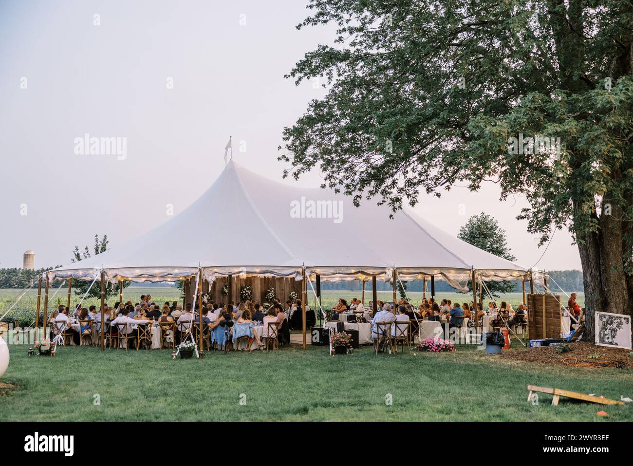 Hochzeitsempfang im Freien unter elegantem Zelt in der Abenddämmerung Stockfoto