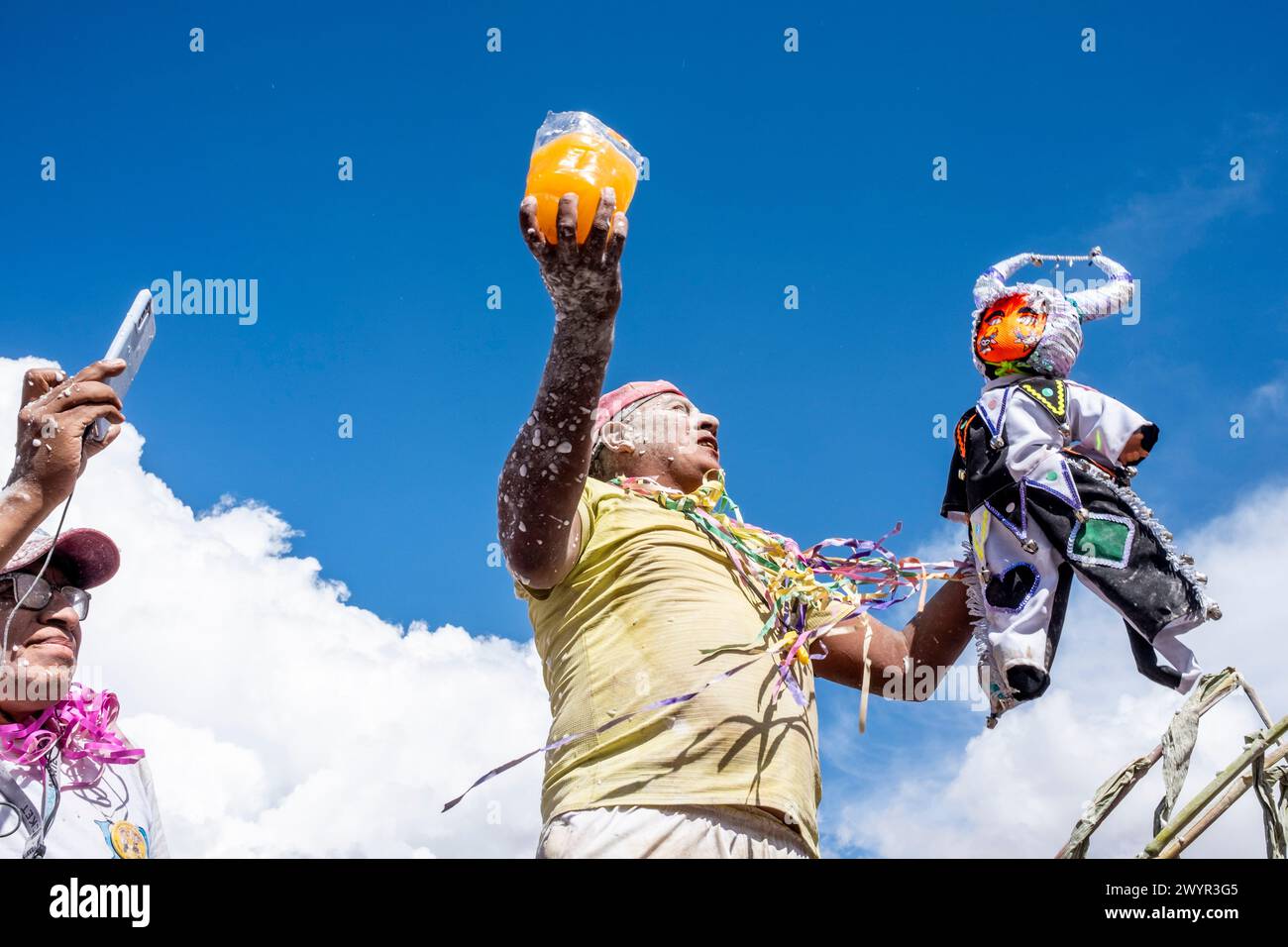 Ein einheimischer Mann bereitet sich darauf vor, während des jährlichen Karnevals in Maimara, Argentinien, ein alkoholisches Getränk über Eine Teufelsfigur, bekannt als Pu Jillay, in Einem Mojon zu gießen. Stockfoto