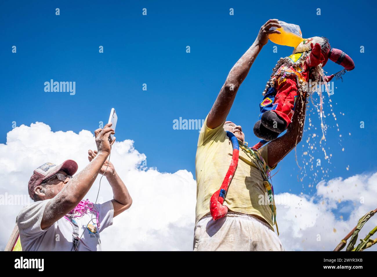 Ein einheimischer Mann gießt während des Karnevals in Maimara, Provinz Jujuy, Argentinien, Ein alkoholisches Getränk über Eine Teufelsfigur, bekannt als Pu Jillay. Stockfoto