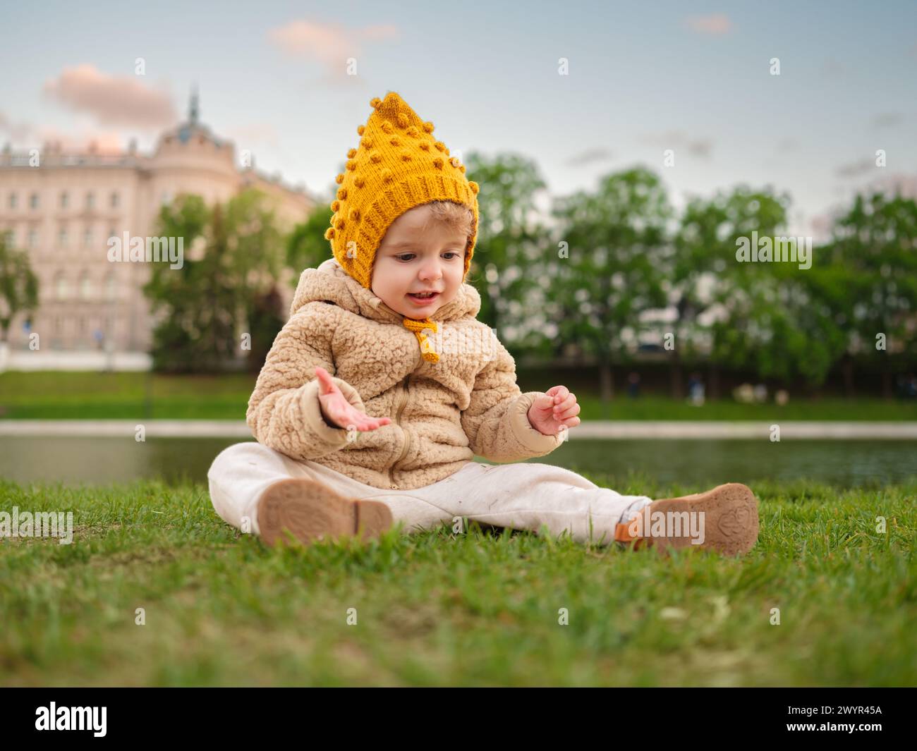 Ein dreijähriges Mädchen sitzt auf dem Gras im Park. Stockfoto