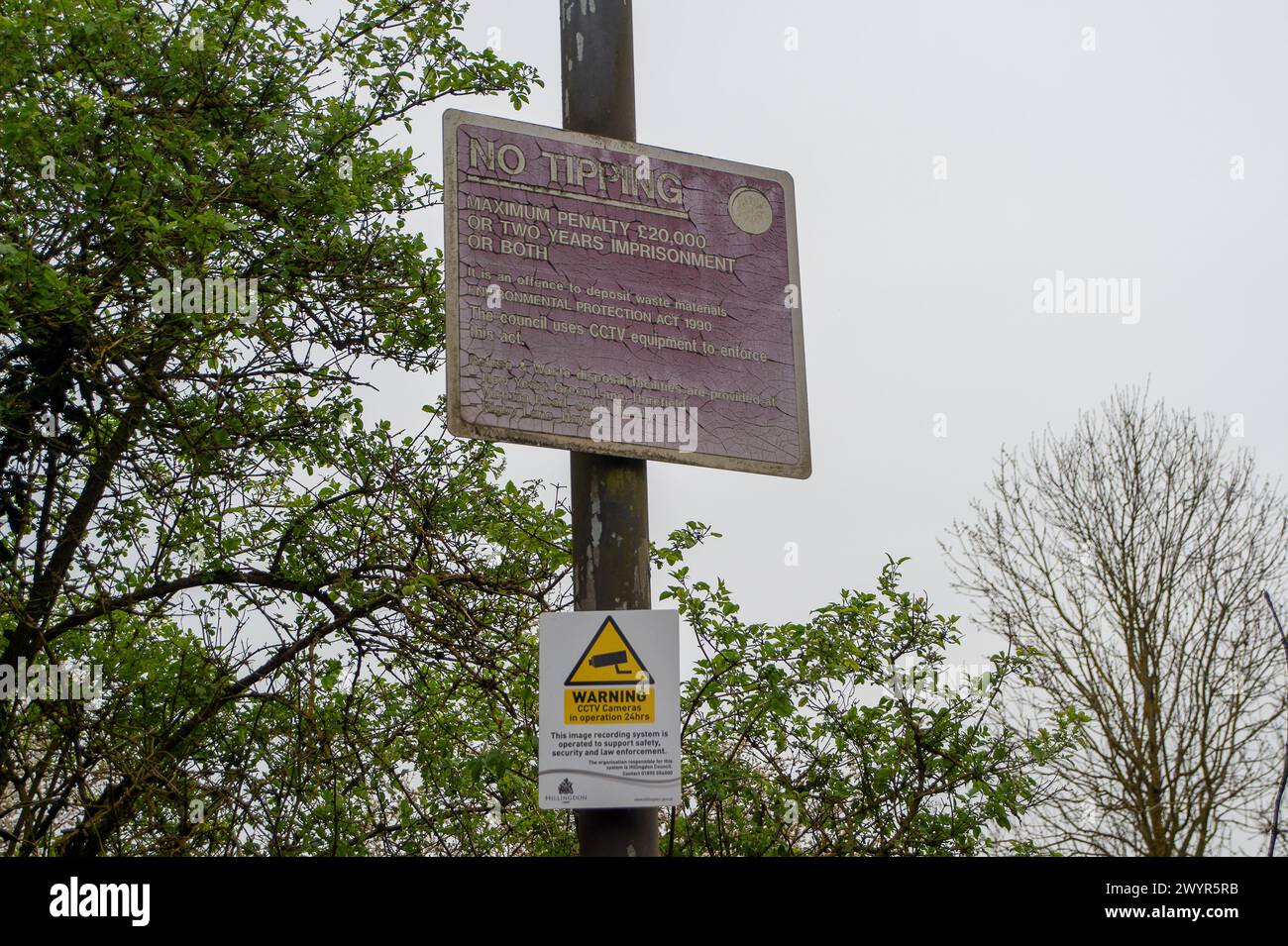 Harefield, Großbritannien. April 2024. Illegale Fliegenkippen auf einer Landstraße in Harefield, Uxbridge, obwohl es nur in der Nähe von Warnschildern für Fliegenkippen und CCTV-Überwachung liegt, die den Menschen sagen, dass sie für Fliegenkippen mit einer Geldstrafe von bis zu 20.000 £ belegt werden könnten. Quelle: Maureen McLean/Alamy Live News Stockfoto