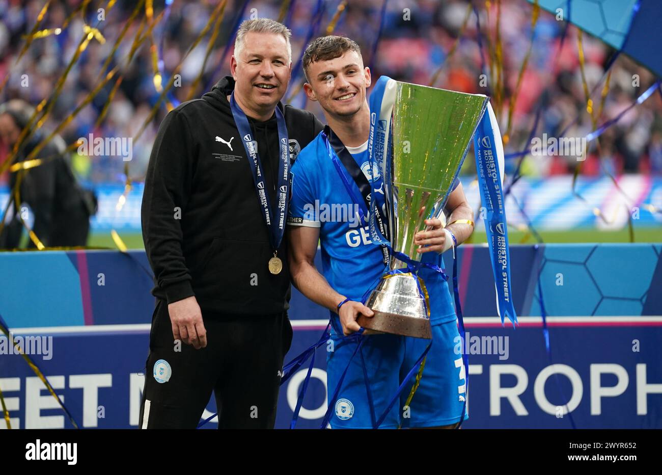 LONDON, ENGLAND – 7. APRIL: Darren Ferguson, Manager von Peterborough United und Harrison Burrows aus Peterborough, Vereinigte sich mit der EFL Trophy Trophy nach dem Bristol Street Motors Trophy Finale zwischen Peterborough United und Wycombe Wanderers am 7. April 2024 im Wembley Stadium in London. (Foto: Dylan Hepworth/MB Media) Stockfoto