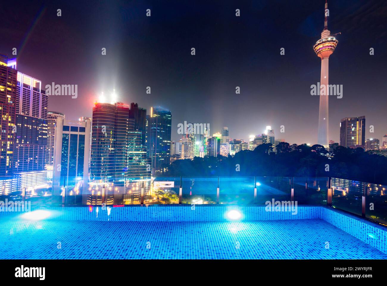 Atemberaubender Blick auf die Wolkenkratzer der Stadt KL, nachts hell beleuchtet, eleganter Pool im Vordergrund mit atemberaubendem Panoramablick Stockfoto