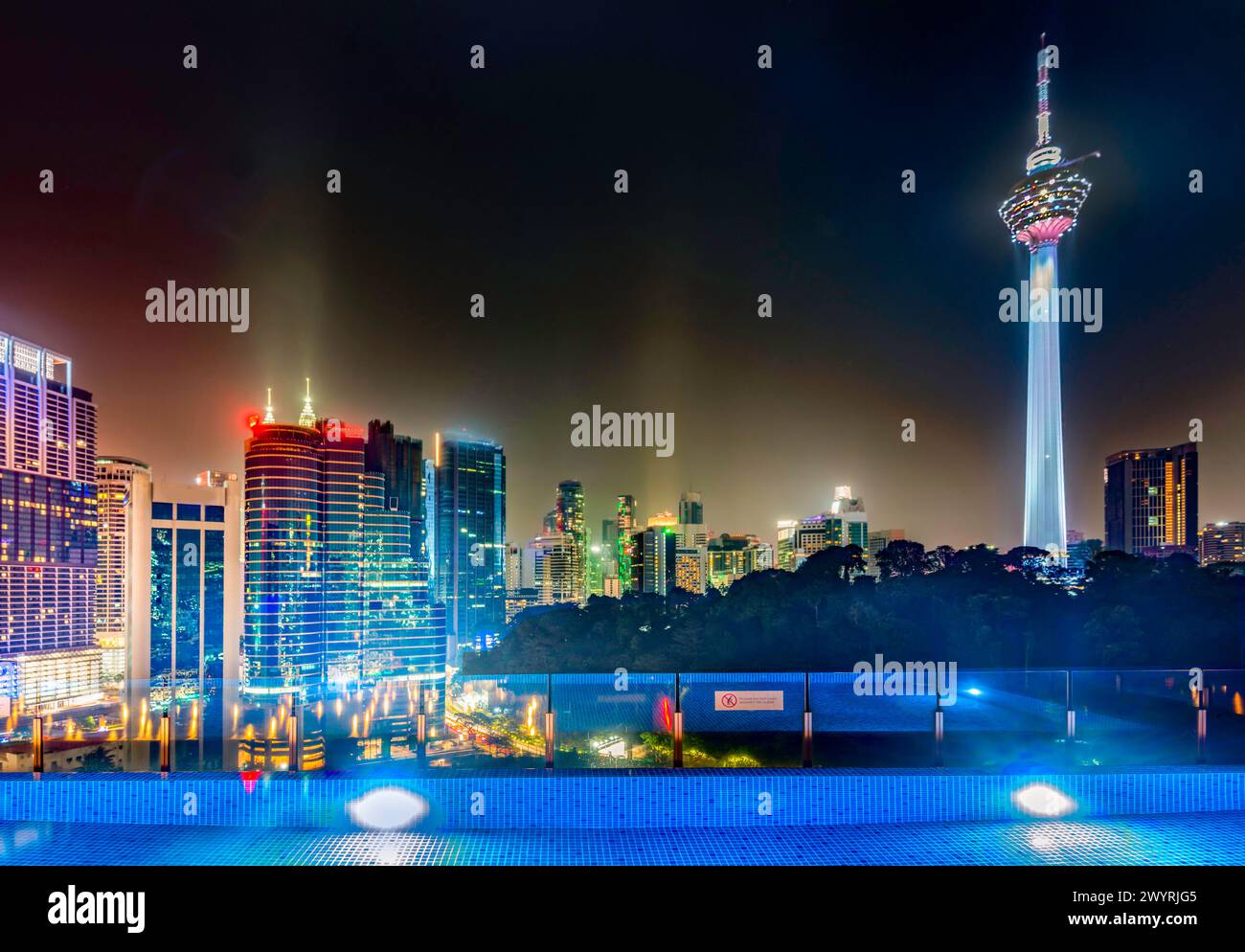 Atemberaubender Blick auf die Wolkenkratzer der Stadt KL, nachts hell beleuchtet, eleganter Pool im Vordergrund mit atemberaubendem Panoramablick Stockfoto