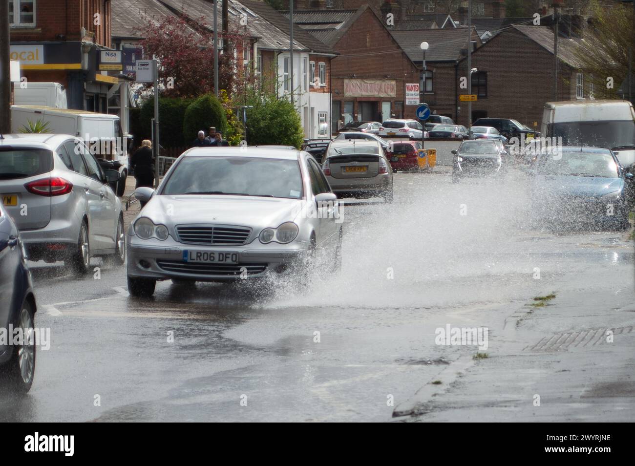 Chesham, Buckinghamshire, Großbritannien. April 2024. Wasser strömt aus einem verstopften Abfluss auf einer Hauptstraße durch Chesham, Buckinghamhire. Einige Autos fuhren schnell durch das Wasser und spritzten Passanten vorbei. Kredit: Maureen McLean/Alamy Stockfoto