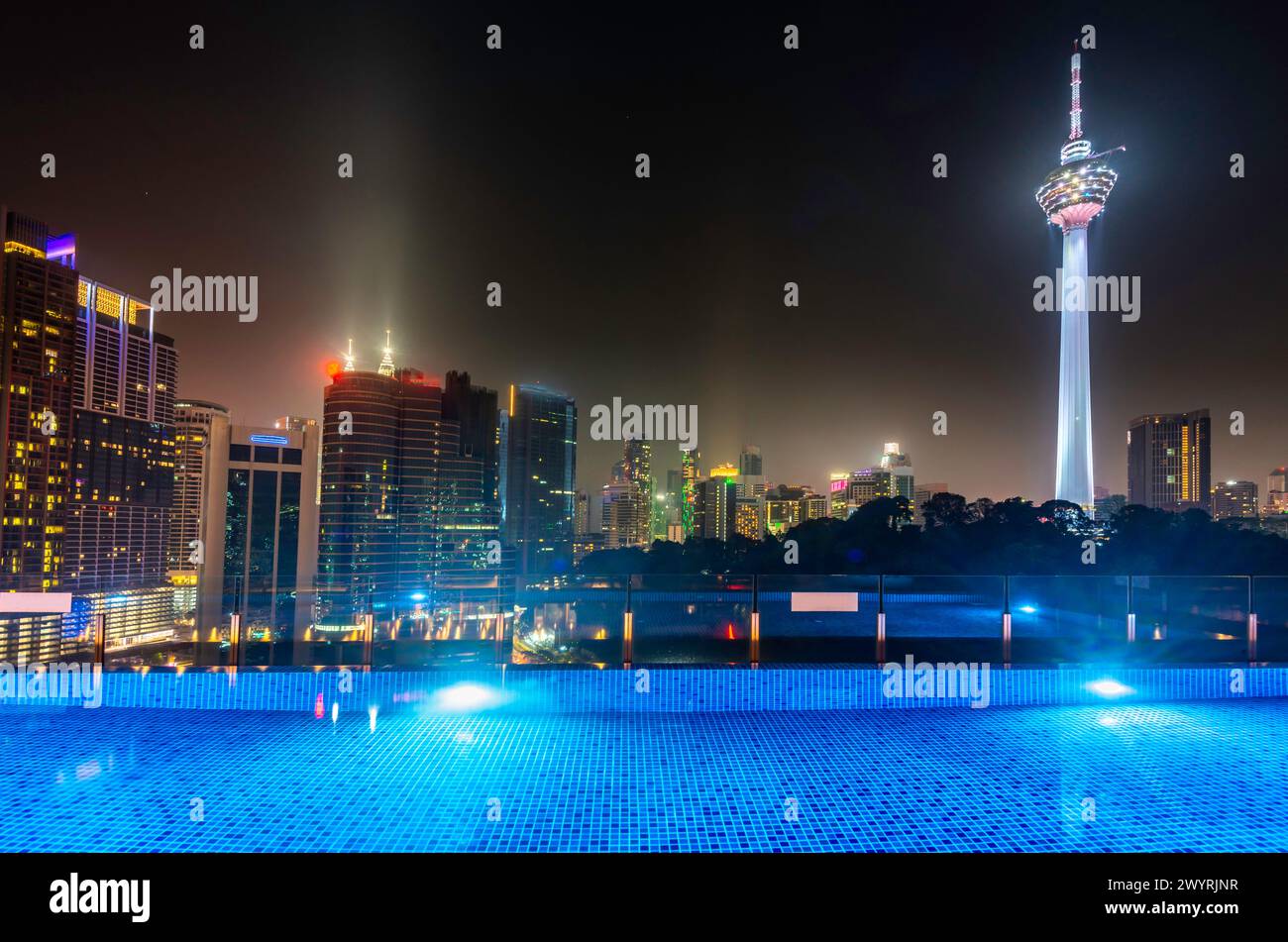 Atemberaubender Blick auf die Wolkenkratzer der Stadt KL, nachts hell beleuchtet, eleganter Pool im Vordergrund mit atemberaubendem Panoramablick Stockfoto