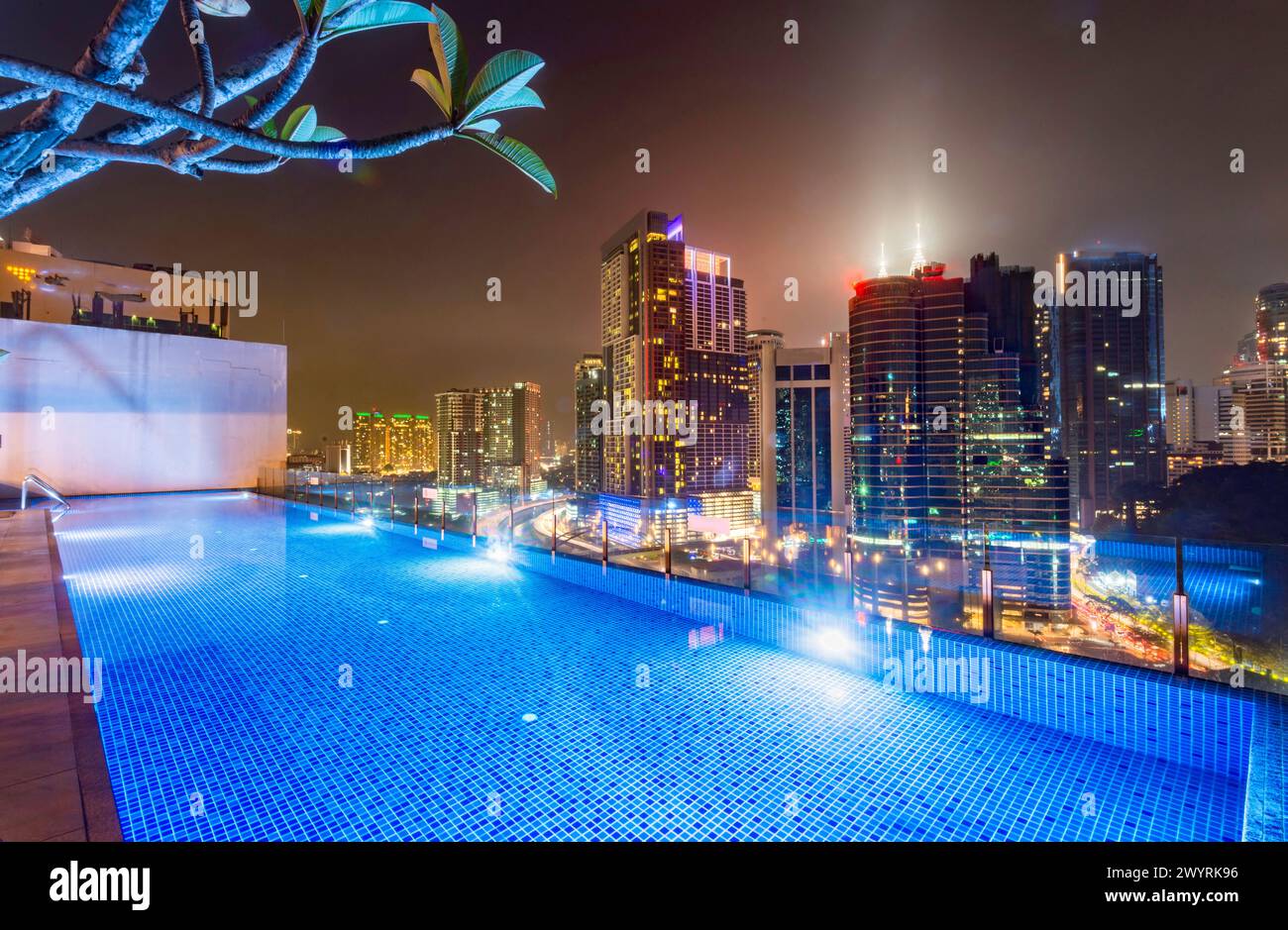 Atemberaubender Blick auf die Wolkenkratzer der Stadt KL, nachts hell beleuchtet, eleganter Pool im Vordergrund mit atemberaubendem Panoramablick Stockfoto