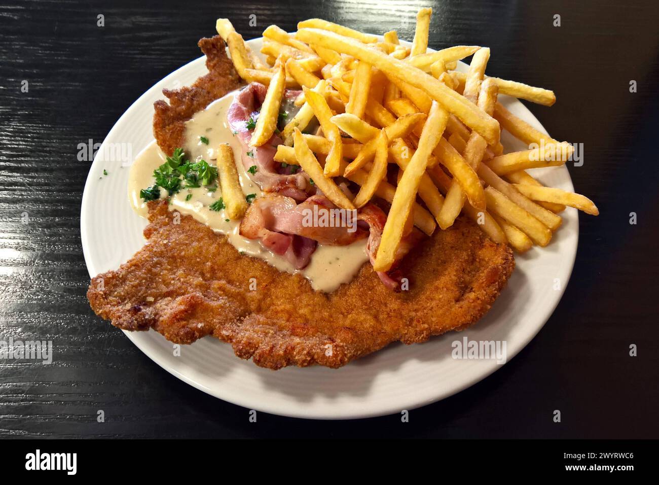 Gastronomie: Paniertes Jägerschnitzel mit Pommes. Das Jägerschnitzel ist ein Gericht der österreichischen Küche. Es ist eine Ableitung des Naturschnitzels, die Normal ohne Panade serviert wird. Im deutschsprachigen Raum versteht man darunter auch oft ein paniertes Kalbs- oder Schweineschnitzel mit einer Pilzsauce *** Gastronomie Jägerschnitzel mit Pommes Frites das Jägerschnitzel ist ein Gericht der österreichischen Küche es ist ein Abkömmling des natürlichen Schnitzels. was im deutschsprachigen Raum normalerweise ohne Panade serviert wird, wird oft auch unter paniertem Kalb- oder Schweineschnitzel verstanden Stockfoto