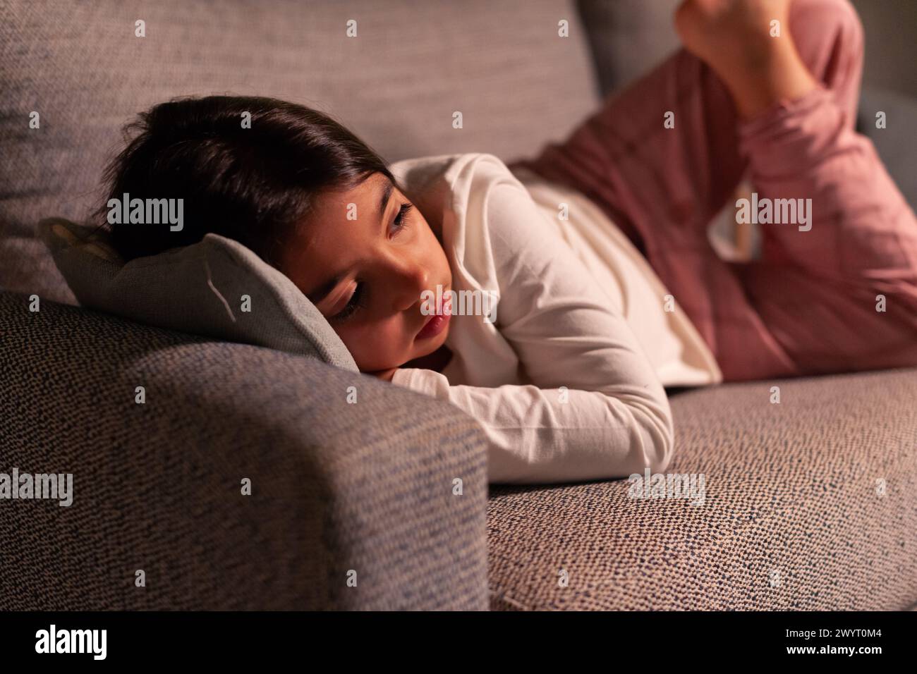 Das Mädchen ruht sich zu Hause auf dem Sofa aus und sieht fern Stockfoto