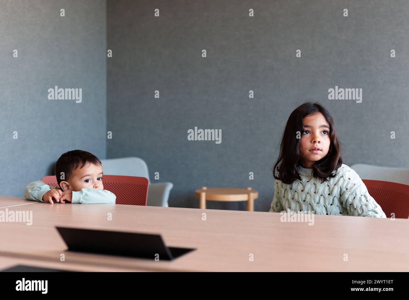 Zwei Kinder, die in einem Büro auf einem Stuhl sitzen Stockfoto