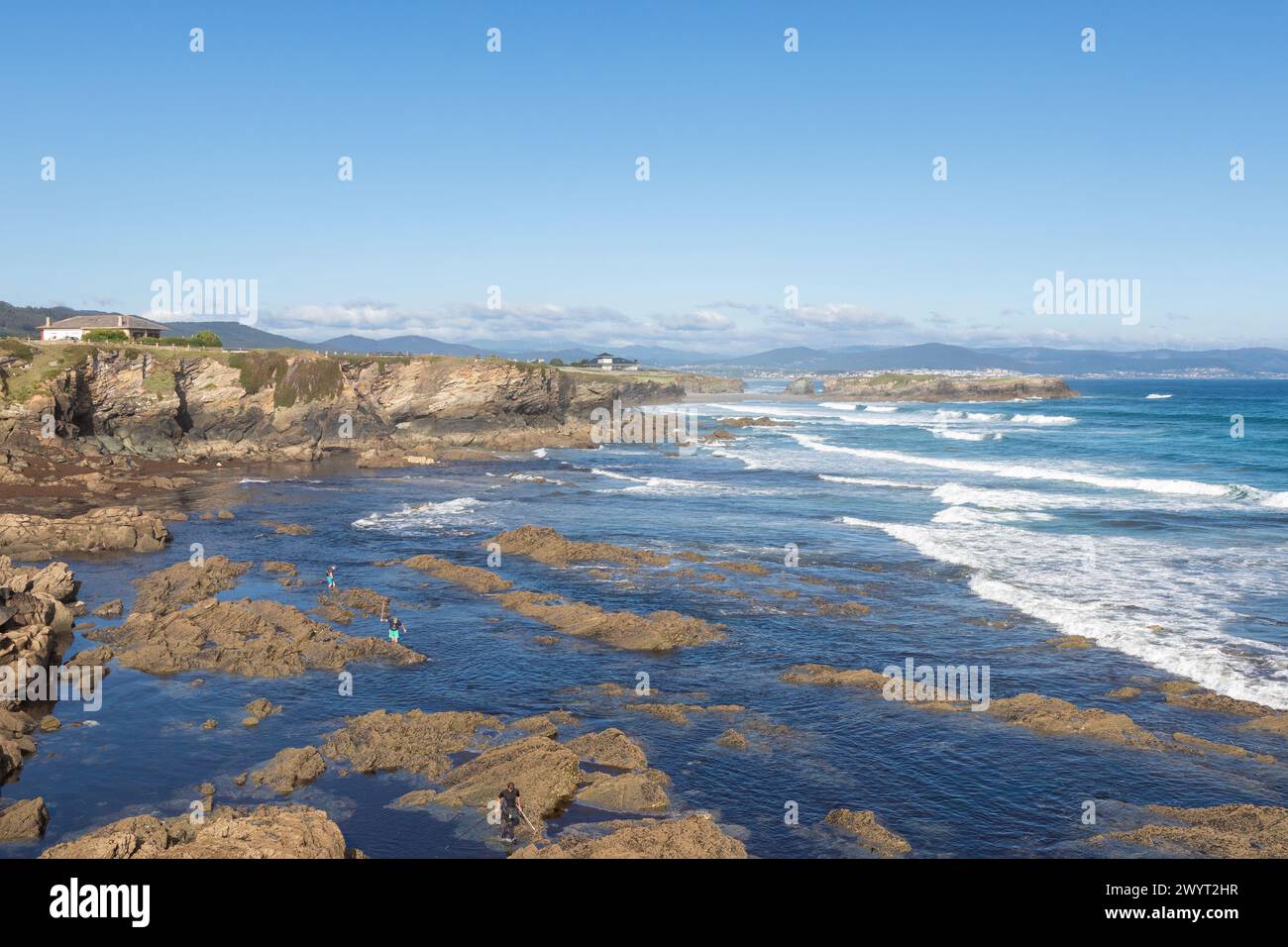 Malerische Küste, felsige Küste, blaues Wasser, Wellen, klarer Himmel, ferne Berge, friedliche Erkundung, unberührte Umgebung. Stockfoto