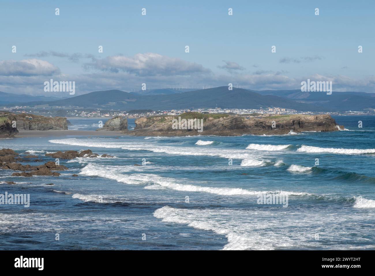 Küste, felsige Küsten, Wellen, klarer Himmel, ferne Berge, friedliche Erkundung, unberührte Umgebung. Stockfoto