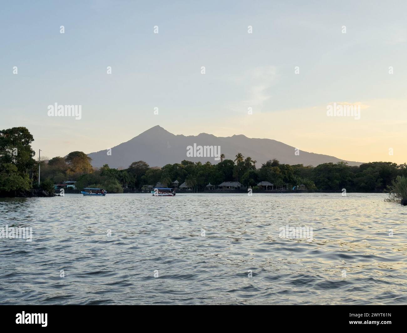 Tropische Bootstour mit vulkanischem Hintergrund bei Sonnenuntergang Stockfoto