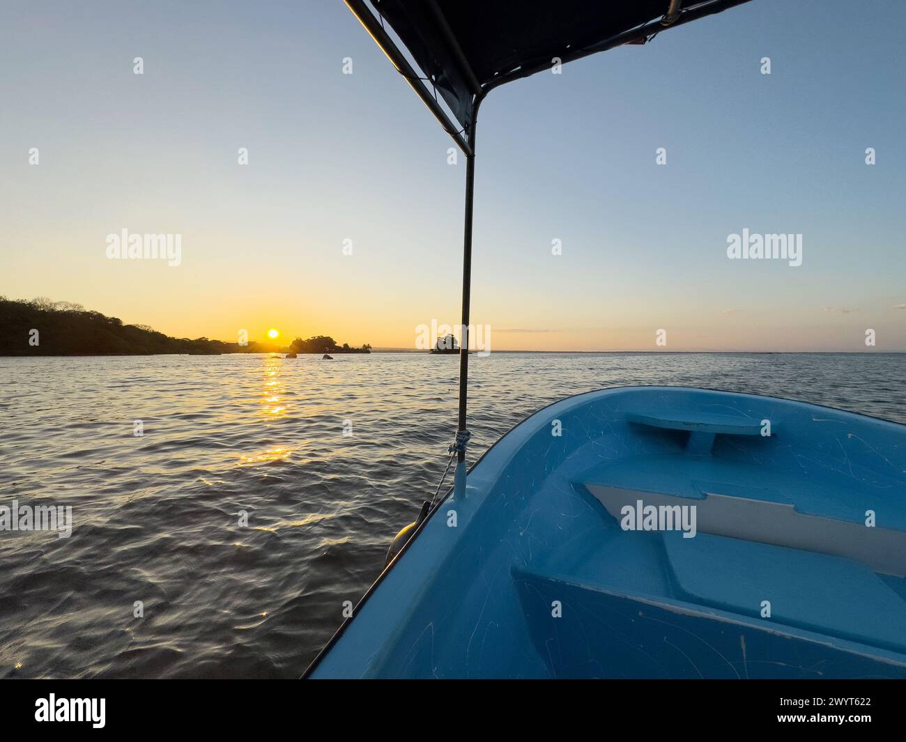 Sonnenuntergang auf dem See Bootstour. Leeres blaues Boot mit Dach im tropischen Hintergrund Stockfoto