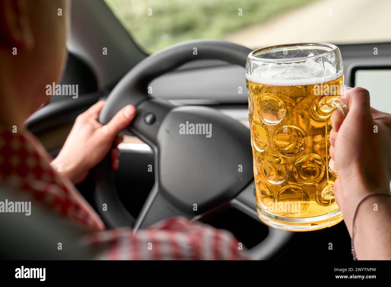 Bayern, Deutschland - 7. April 2024: Ein Mann in bayerischer Tracht, Hemd und Lederhose trinkt ein Bier am Steuer eines Autos. Symbolbild des Fahrens unter Alkoholeinfluss nach einem Volksfest *** ein Mann in bayerischer Tracht, Hemd und Lederhose trinkt eine Maß Bier am Steuer von einem Auto. Symbolbild Akoholfahrt nach einem Volksfest Stockfoto