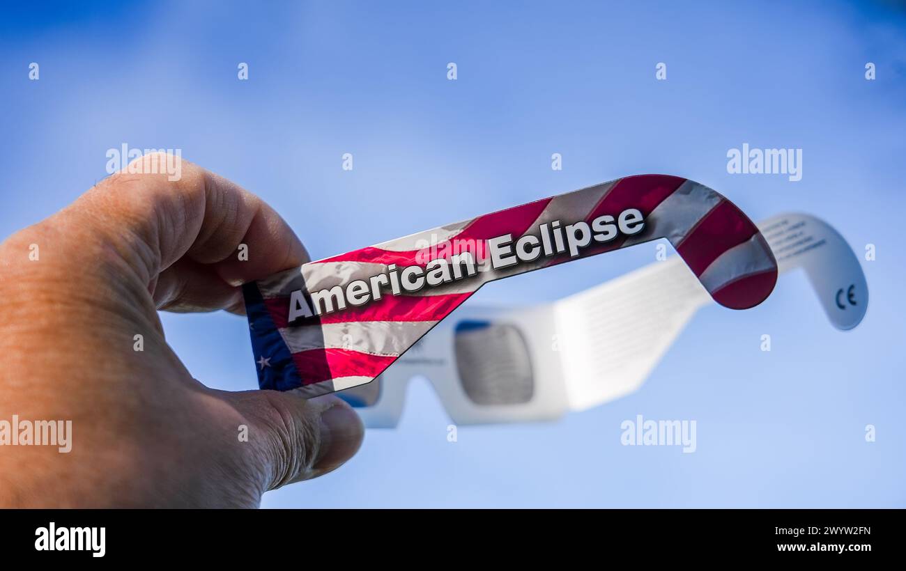 NORWALK, CT, USA - 8. APRIL 2024: Eine Hand hält eine Sonnenfinsternis-Brille, auf der die amerikanische Eclipse aufgedruckt ist und mit der Flagge der Vereinigten Staaten verziert ist Stockfoto
