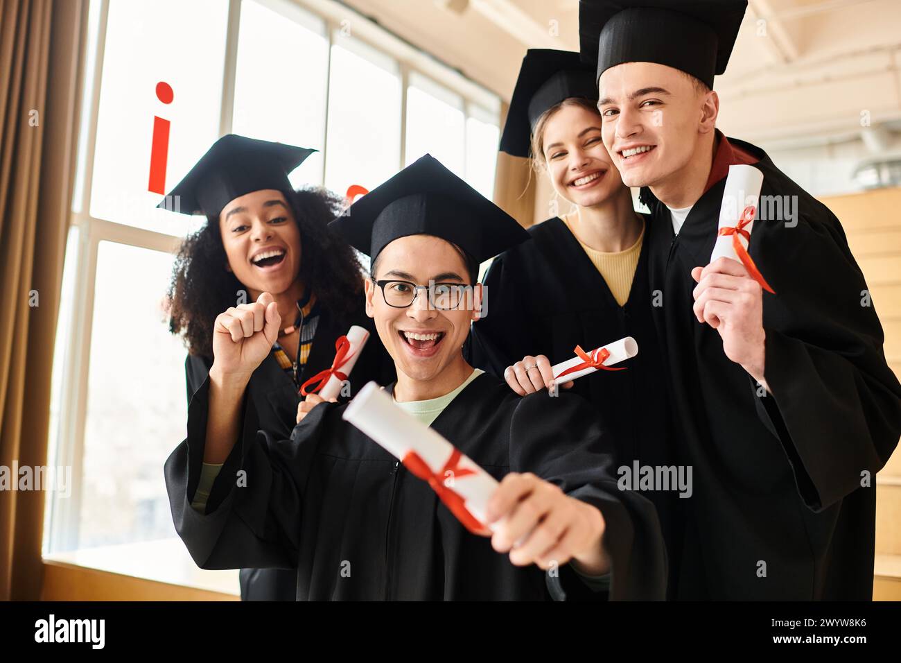 Eine vielfältige Gruppe von Studenten in Abschlusskleidern und -Mützen posiert freudig für ein Foto, um ihren akademischen Erfolg zu gedenken. Stockfoto