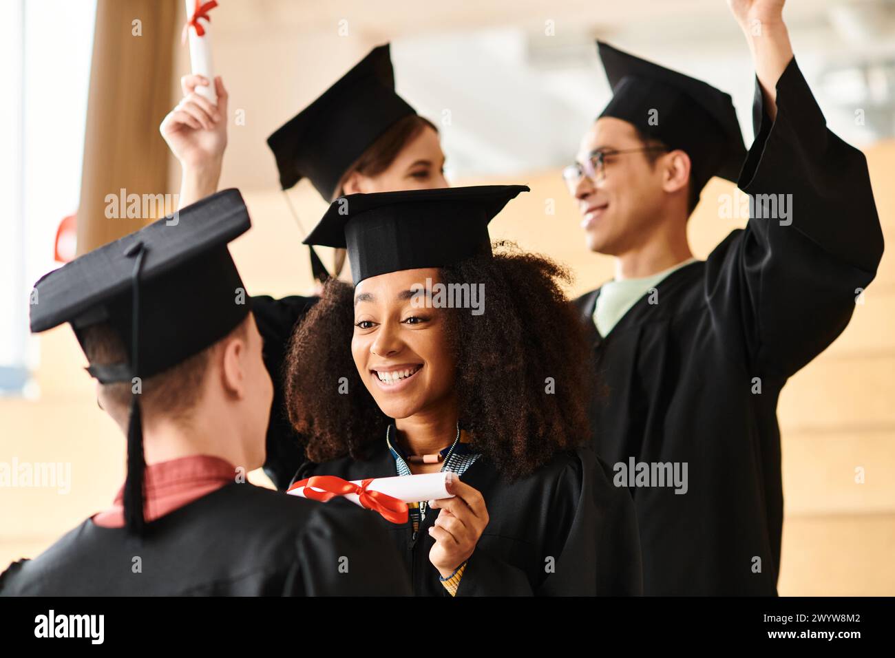 Eine Gruppe junger Menschen mit unterschiedlichem Hintergrund feiert in Abschlusskleidern bei einer Universitätszeremonie. Stockfoto
