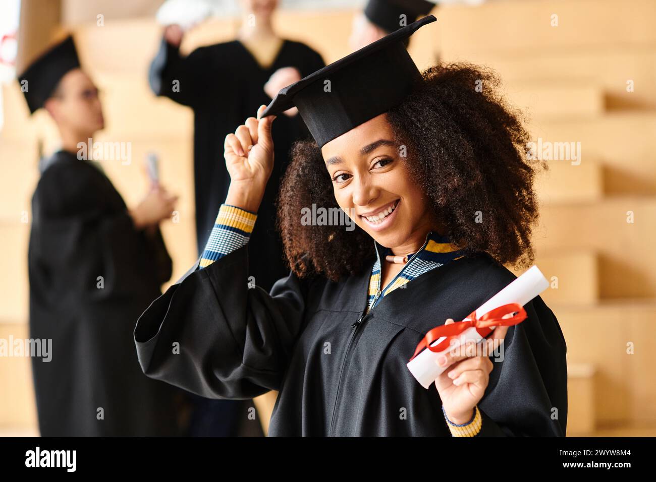 Eine vielfältige Gruppe von Absolventen feiert mit Freude in ihren Mützen und Kleidern bei einer Abschlussfeier an der Universität. Stockfoto